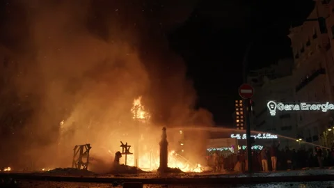 Water hose dousing falla sculpture ruins during Las Fallas La Crema night Stock Footage 334296948