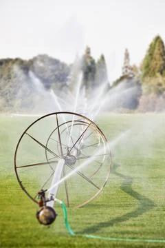 Water hoses on round frames spraying water jets in a field, commercial hortic 写真素材