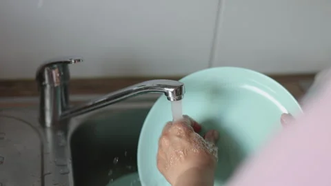 Water jet pouring flows over fresh vegetables in kitchen sink. Stock-Footage 242990868