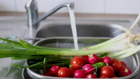 Water jet pouring flows over fresh vegetables in kitchen sink. Stock-Footage 242990877