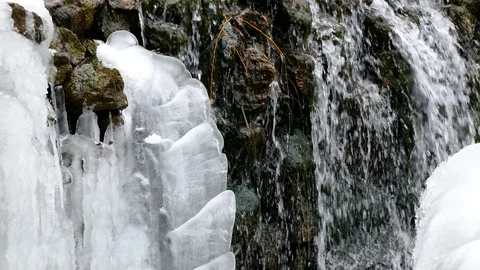 Water jets flow down the stones of a waterfall in winter 스톡 동영상 123572764