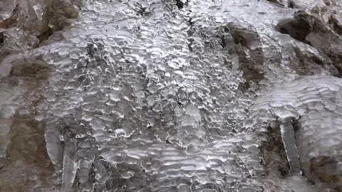 Water leaking from melting ice beneath an ice layer covering a rock surface Stock Footage 339558558