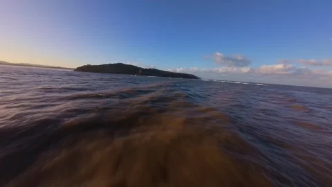 Water-level perspective captures sunlit waves and distant island Stock Footage 344577558