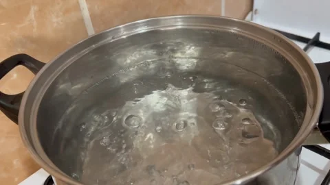 Water in a metal pot boils, bubbles of bubbling water when boiling Stock Footage 255040057