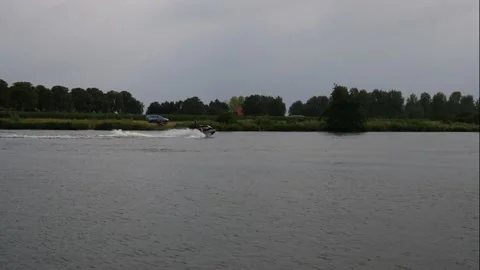 Water motorcycle is going upstream, a small cruiser is salling downstream Stock Footage 141292297