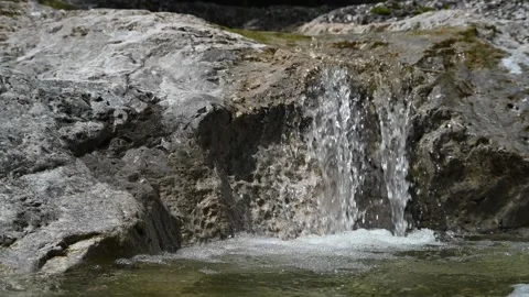 Water from a mountain river is falling into a pool in the sunshine (slow motion) Stock-Footage 212733639
