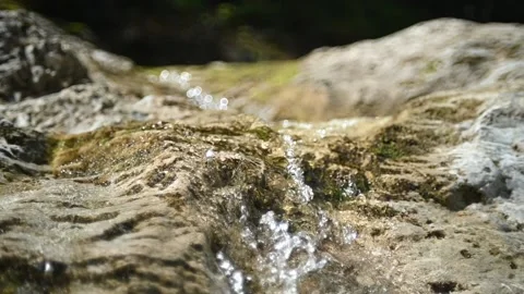 Water from a mountain river is falling into a pool in the sunshine (slow motion) Stock Footage 212734020