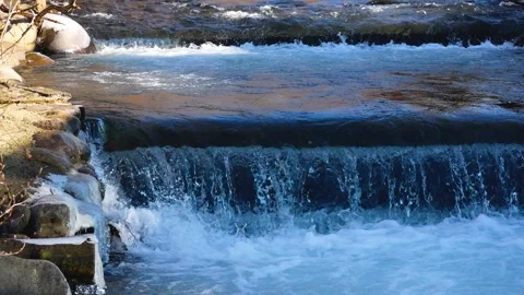 The water in the mountain river flows down and falls from a small ledge Stock Footage 267132891