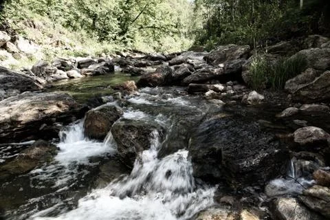 Water of mountain river flows down from the rocks Stock Photos