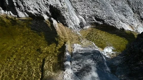 Water from a mountain stream flows out of a pool into the next one (slow motion) Stock Footage 219645968