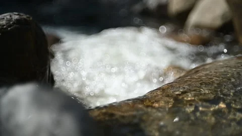 Water from a mountain stream flows over rocks in sunlight (slow motion, bokeh) Stock-Footage 219392299