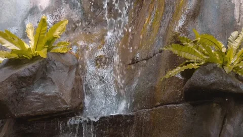 Water from a mountain waterfall falls down a rock, splashes slowly flying around Stock Footage 303302590