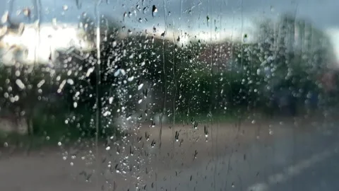 Water moves across a bus window with a road and rural buildings visible beyond t 스톡 동영상 341408570