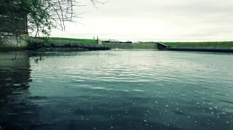 Water Moving with Dam in Background and Brush in Foreground Stock Footage 62867944