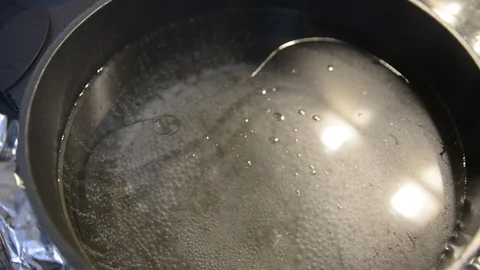 Water with olive oil boiling in black pot. Abstract close-up on the surface of b Vídeos de archivo 101078908