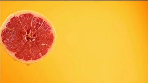Water or oils falling into a slice of a grapefruit, fruit for diet and health Stock Footage 128897028