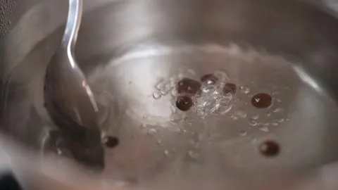 Water with pepper in a saucepan boils while it is stirred with a spoon. Stock Footage 250010135