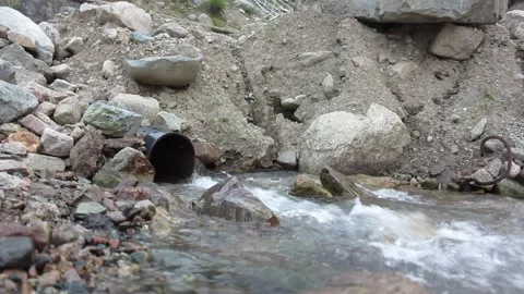 Water from a pipe dump in the mountain river Video stock 124615503