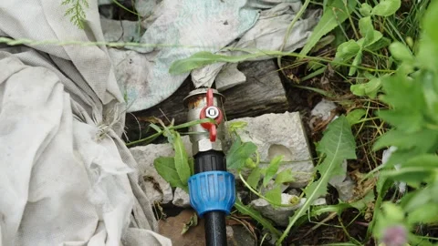 Water pipe with red valve switch laying on the ground Stock Footage 338200888