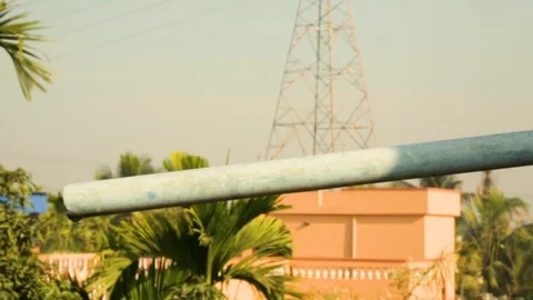 Water pipe of a rooftop water tank against a high tension electric pole. Stock Footage