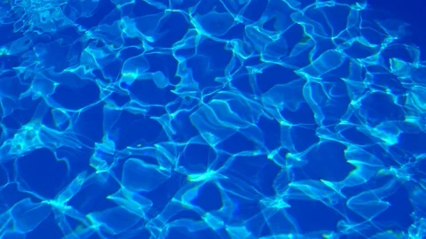 Light Blue swimming pool rippled water texture reflection. Beautiful blue  water background with glare from the sun. Stock Photo