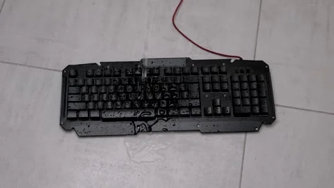 Water is poured on a computer keyboard during a cleaning process in a kitchen Stock Footage 343035424