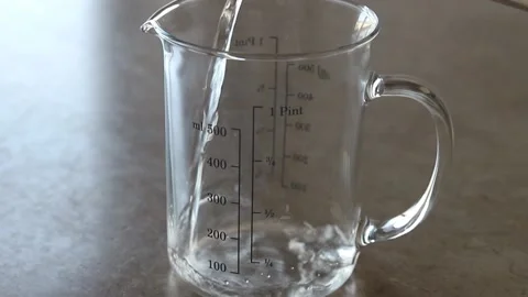 Water is poured into a measuring cup Stock Footage 133648456