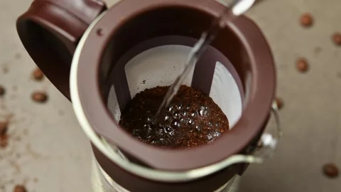 Water is poured over coarse coffee grounds in a cold brew filter, wetting the Stock Footage 346743750