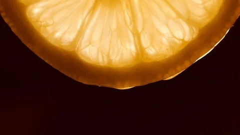 Water pouring on half slice cut of fresh lemon against black background Stock Footage 127853215