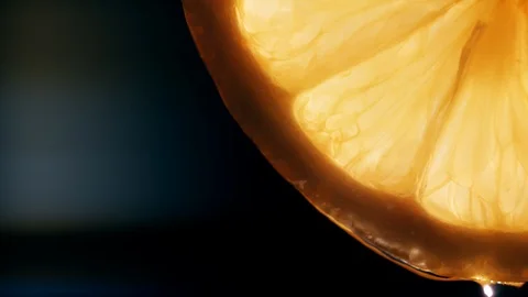 Water pouring on half slice cut of fresh lemon against black background Stock Footage 127854500