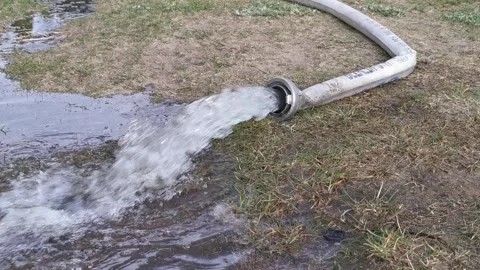 Water pouring from a hose, pulling water out of a flooded house Stock Footage 306723406
