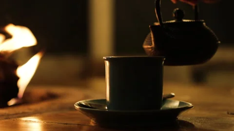 Water pouring from kettle to cup background fire. Video stock 273464715