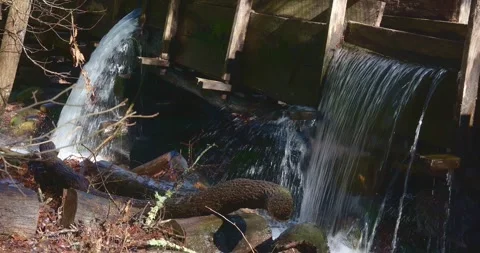 Water pouring out between boards of an old wood mill race or sluice. Stock Footage 280148744