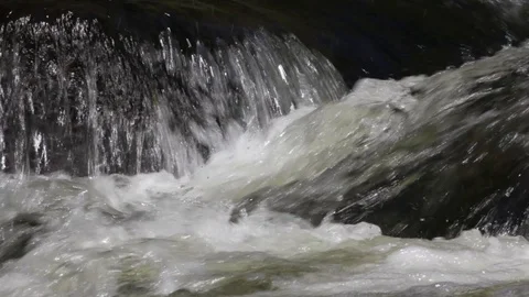 Water pouring over rocks in an upland stream Stock Footage