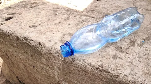 Water Pouring from Plastic Bottle onto Concrete Edge Stock Footage 333683494