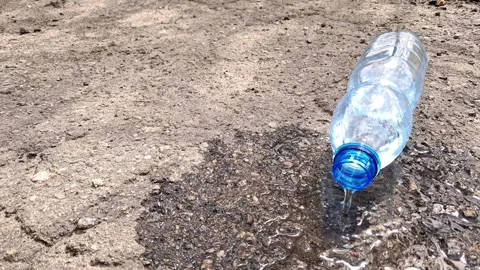 Water Pouring from Plastic Bottle onto Dry Ground Stock Footage 333683055