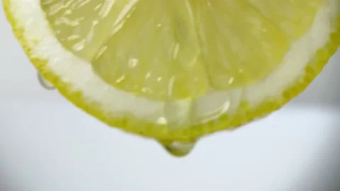Water pours on half a slice of fresh lemon on a white background Stock Footage 236503456