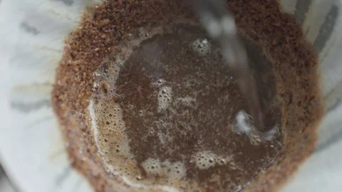 Water pours over coffee grounds in a paper filter during pour over coffee setup Stock Footage 337957608
