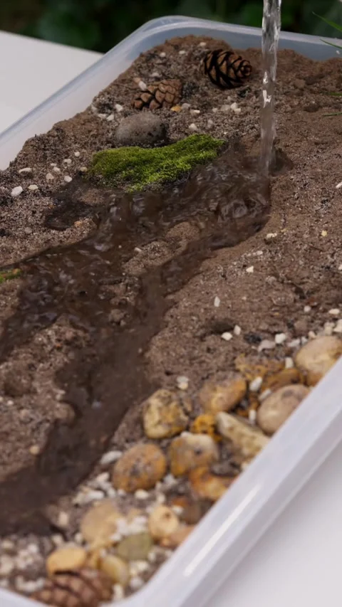 Water pours into sand tray creating a small stream Video stock 331769915