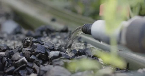 Water pressure is forcing clear stream from pipe nozzle onto crushed stones for Stock Footage 338357012