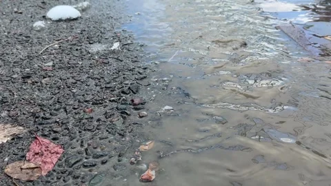 Water puddle on rough asphalt road surface outdoors, wet street texture after Stock Footage 336960385