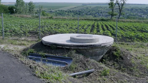 Water pump and storage system in rural area, surrounded by green fields and Stock Footage 312739258
