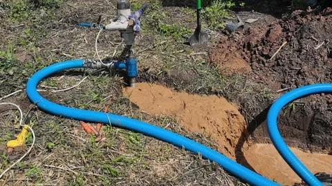 Water pump system working in the field to remove mud from the hole at midday Video stock 336153318