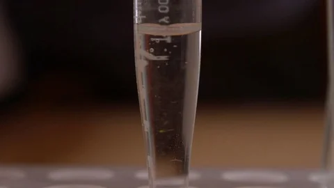 Water purification test. Drop orange liquid in test tube with clean water Stockbeeldmateriaal 71641740