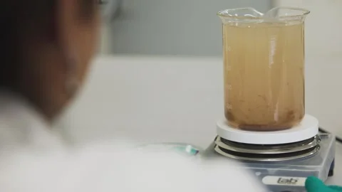 A water quality scientist observes a beaker of murky liquid undergoing Stock Footage 315126354