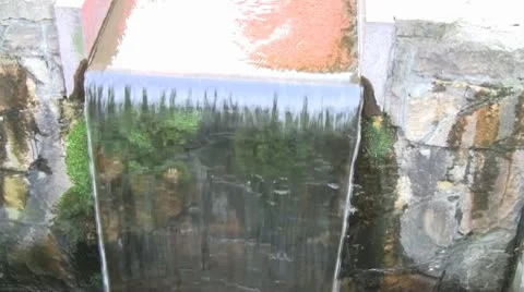 Water quickly flows down the mossy steps of an artificial waterfall Stock Footage 10584426