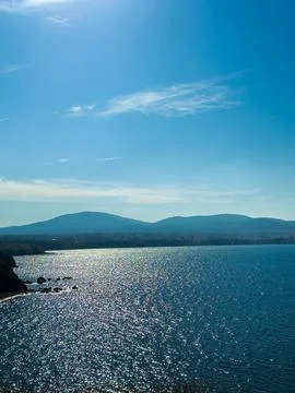 Water reflects sunlight with shimmering patterns under a clear blue sky. Hill Photos
