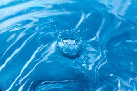 Water ripple background. Splashes from a drop of water. Raindrops on a blue b Foto stock