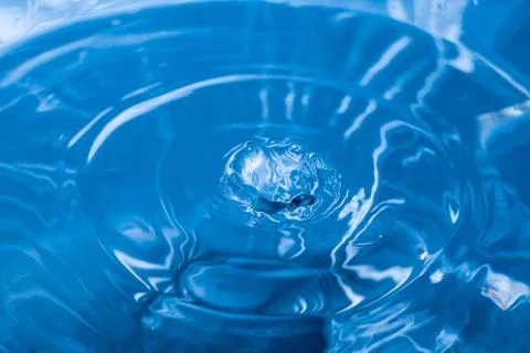 Water ripple background. Splashes from a drop of water. Raindrops on a blue b 写真素材