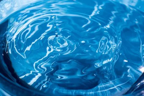 Water ripple background. Splashes from a drop of water. Raindrops on a blue b 写真素材